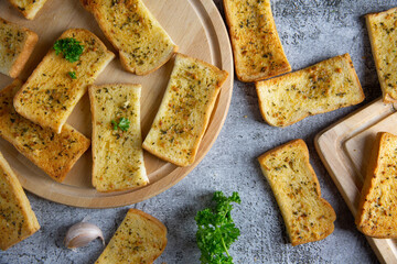 Wooden cutting board with delicious homemade garlic bread on the cement floor