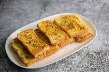 Plate with delicious homemade garlic bread on the cement floor