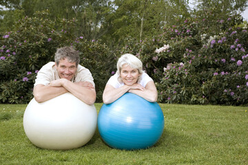 Fototapeta na wymiar Senior man and woman resting on fitness ball