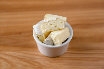 Cut cheese in a small white bowl. Snack, appetizer. Pizza ingredient.