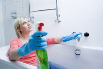 Woman sitting in the bathtub after cleaning the bathroom