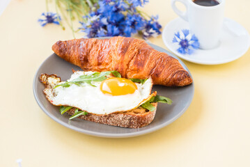 Breakfast. Plate with fried egg and french croissant with aromatic coffee 