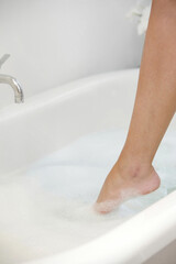 Woman's leg stepping into bathtub
