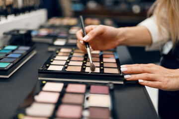 Woman with brush choosing shadows, cosmetics store