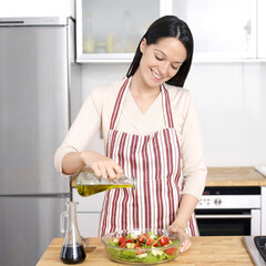 Woman pouring olive oil into salad