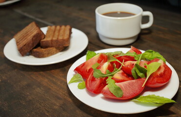 Sliced tomatoes with lettuce on a white plate. Fresh bread toast. Healthy eating concept
