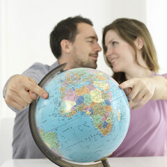 Man and woman pointing at globe