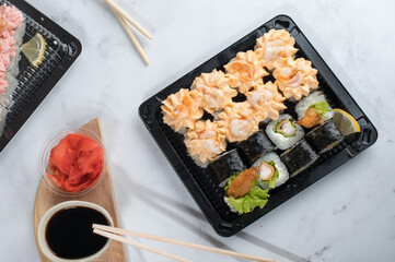 Sushi roll set with yellow cream sauce and shrimp in take away boxes