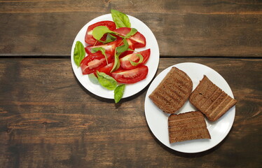 Sliced tomatoes with lettuce on a white plate. Fresh bread toast. Healthy eating concept