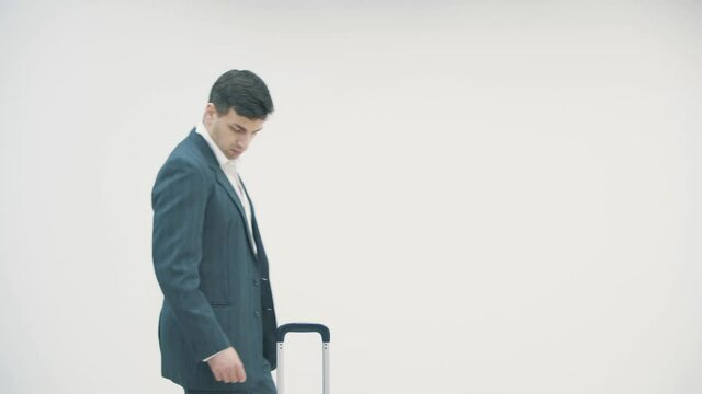 Young businessman found a suitcase that somebody left in the airport over white background.