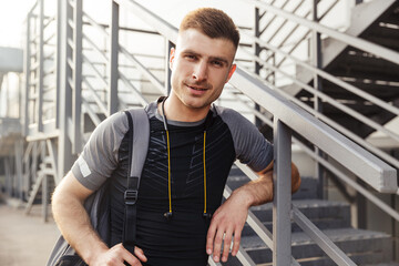 Image of sportsman looking at camera while bending over railing