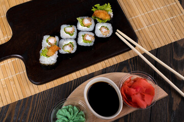 Sushi roll set with salad and fried shrimp on dark background