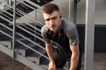 Image of unshaven athletic sportsman using earphones while working out