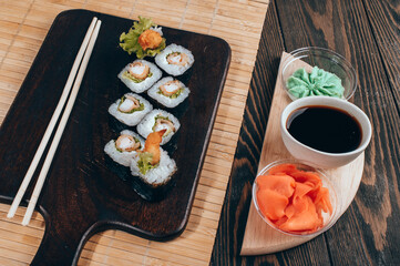 Sushi roll set with salad and fried shrimp on dark background