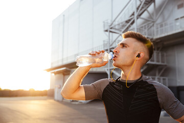 Image of young athletic sportsman drinking water while working out