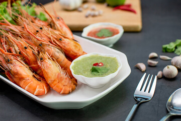 Grilled river prawns on a plate with sauce, onions, garlic, peppers and condiments