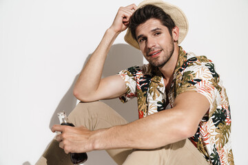 Portrait of cheerful young man drinking soda while sitting on floor