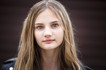 Fototapeta premium close-up portrait of little beautiful stylish kid girl with long flowing hair against a brown striped wall