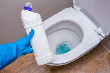 Clean toilet with cleaning agent bleaching gel and a gloved hand