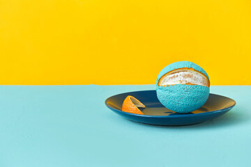 painted orange in blue on a plate. peeled slice of peel. yellow background. copy space