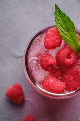 Fresh ice cold berry juice drink with mint, summer raspberry lemonade in glass on stone concrete background, top view macro