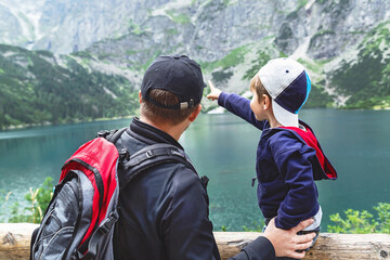 Father and his son near the Eye of the Sea lake in Tatra mountains. Happy enthusiastic boy is pointing to the mountains. © MarKord