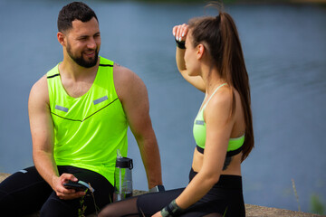 Athletic couple girl and man fitness instructors rest and drink water after street training, photo for sport blog or ad