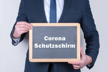 Geschäftsmann mit einer Tafel auf der Corona Schutzschirm steht