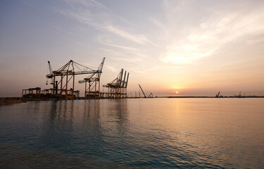 Fototapeta na wymiar Cranes in seaport at sunrise.