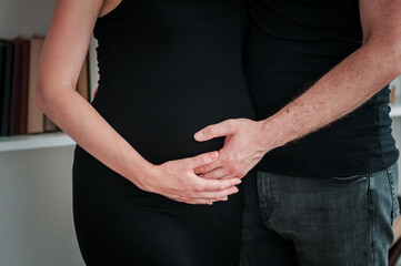 hands of man and woman on pregnant belly