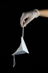 mano sosteniendo mascarilla sobre fondo negro