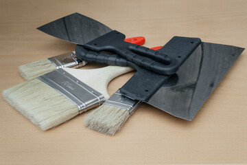 Tool for painting work. Spatula and brushes. Set of items for repair. Top view of a builder with a brush and spatula for applying putty on wood.