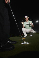 Fototapeta na wymiar Two men playing golf at night