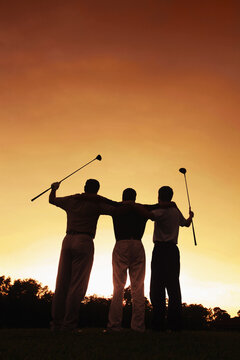 Three men at golf course during sunset