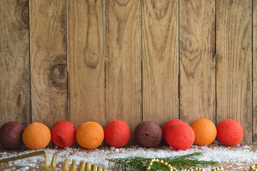 Chirstmas and New year greeting card with orange, yellow fabric balls on snow and old wooden background. Space for text