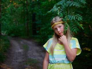 portrait of a blonde girl with blue eyes in green thickets