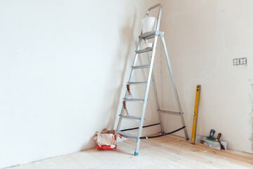 A stepladder with painting tools in a room. Preparing for putty