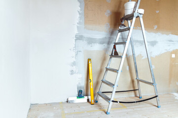 A stepladder with painting tools in a room. Preparing for putty