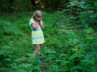 portrait of a blonde girl with blue eyes in green thickets