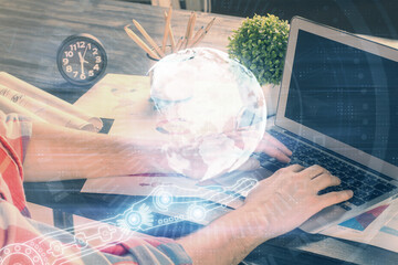 Double exposure of world map hologram with man working on computer on background. Concept of worldwideweb.