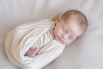 Maternal hands hold baby legs on the bed at home. Happy and healthy motherhood. Child care