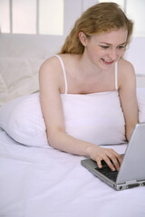 Fototapeta na wymiar Woman lying forward on the bed using laptop