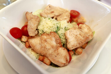 Caesar salad with chicken breast on white plate