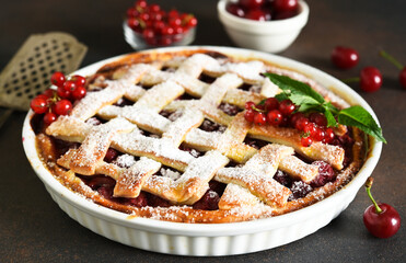 Cherry pie sprinkled with icing sugar on a wooden, brown background.