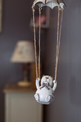 clay figurine of a white cat swinging on a swing, in the background a night lamp. selective focus image.
