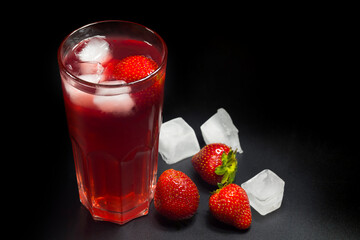 Summer strawberry lemonade on a black background. Fruit lemonade with ice.