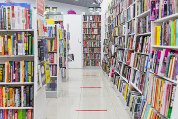Books on shelves in a store. A large assortment of literature. Blurred. Marking on the floor to maintain customer distance during the coronavirus pandemic.