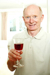 Senior man smiling while holding a glass of red wine