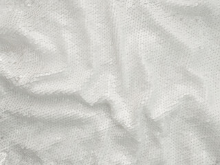 Background fabric sequin in white color. Holiday abstract glitter background with blinking lights. Fashion fabric glitter. 