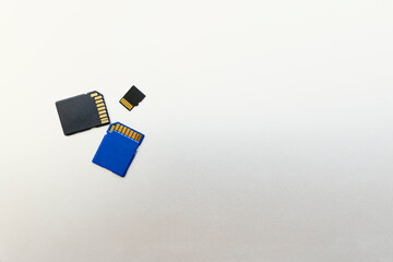 three memory Cards for digital cameras and devices and on a gray metal surface,  copy space for text.